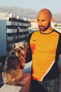 Portrait of man with dog against sky in city