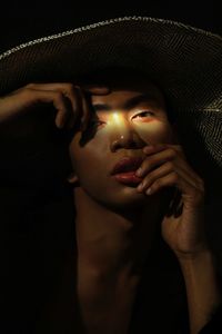 Close-up portrait of young woman against black background