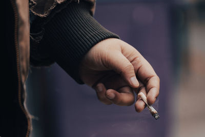 Close-up of hand holding cigarette