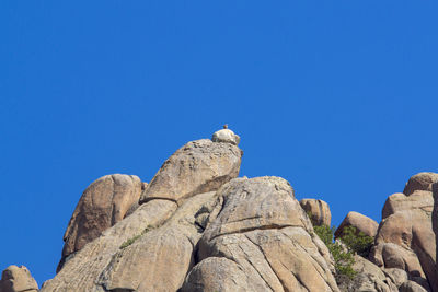 Low angle view of rock formation against clear blue sky