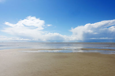 Scenic view of beach against cloudy sky