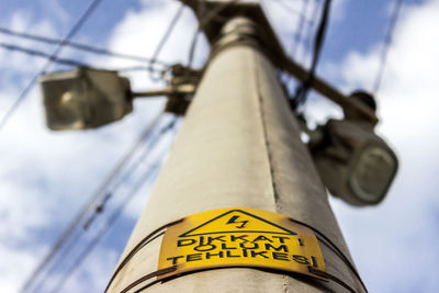 Low angle view of high voltage sign on power line