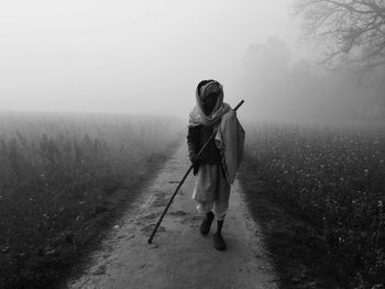 Senior man walking on footpath amidst field