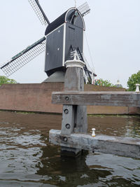 Traditional windmill by river against sky