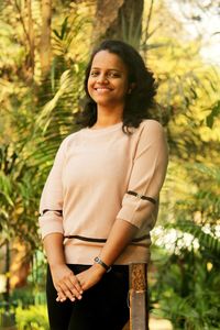 Portrait of smiling young woman standing against trees