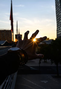 Hand against sky at sunset