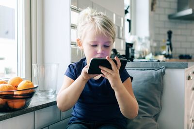 Girl surfing net while sitting by window at home