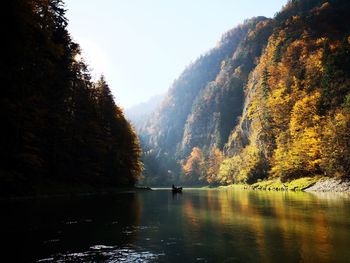 Scenic view of lake in forest against sky with person in boat