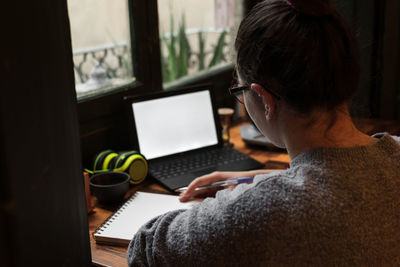 A young student works on a table near a pub window. close up view