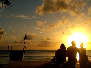 Silhouette people on beach against sky during sunset