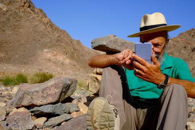 Rear view of man sitting on rock