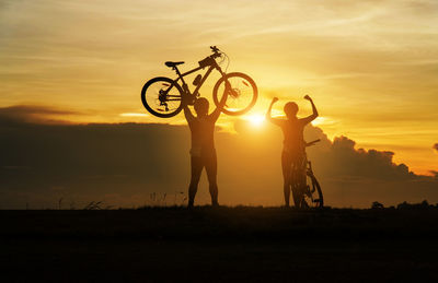 Silhouette people standing on field against sky during sunset