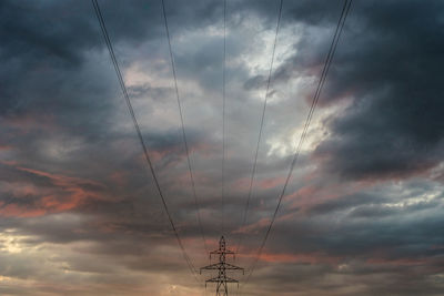 Low angle view of electricity pylon against dramatic sky
