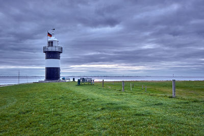 Lighthouse by sea against sky