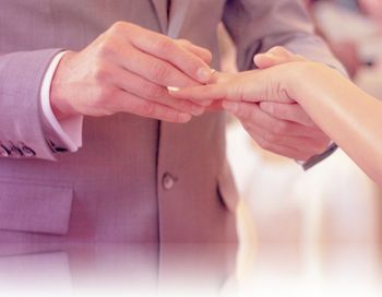 Man sliding ring on woman finger during marriage ceremony