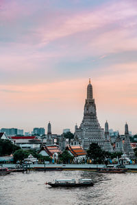 River amidst buildings against sky during sunset