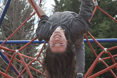 Portrait of young woman hanging on jungle gym at playground