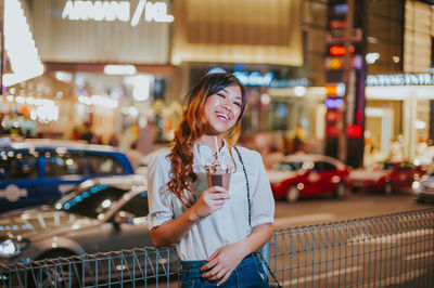 Portrait of smiling young woman standing in city