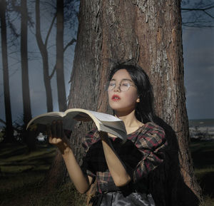 Young woman looking at tree trunk