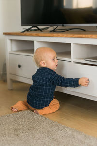 Cute baby boy sitting on floor at home