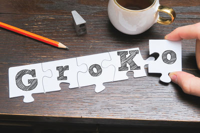 High angle view of person holding paper with text on table