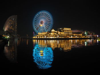 Illuminated ferris wheel in city at night