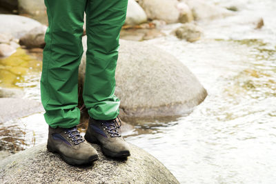 Low section of man standing on rock by lake