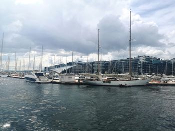 Sailboats moored at harbor against sky