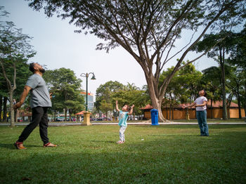 People playing on field against trees