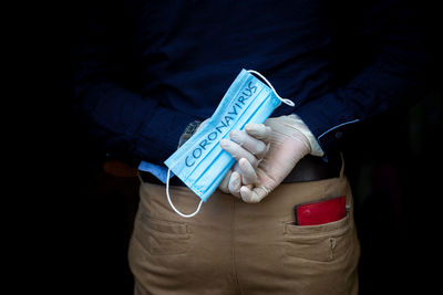 Midsection of woman holding smart phone against black background