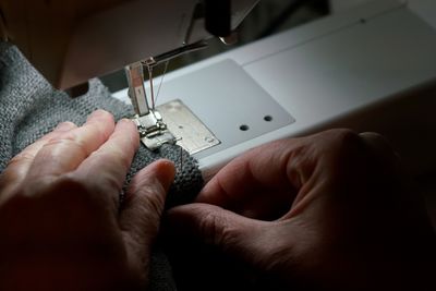 Cropped hand of person repairing sewing machine
