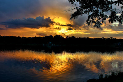 Scenic view of lake against cloudy sky during sunset