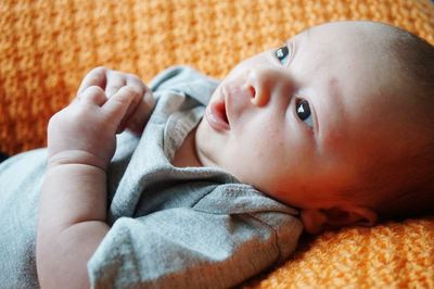 Close-up of baby boy looking away while lying on bed
