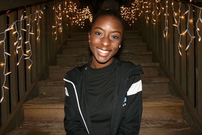 Portrait of smiling teenage girl sitting on steps at home