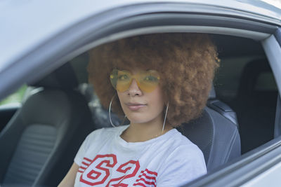 Woman with afro hair sitting in her car
