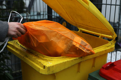 Cropped hand putting garbage in bin
