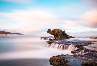 Scenic view of waterfall against sky during sunrise