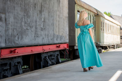 Rear view of woman walking on railroad station platform by train
