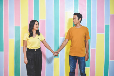 Full length of a smiling young woman standing against wall