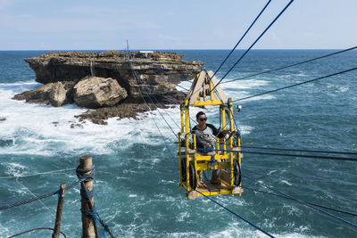 Person in overhead cable car above sea