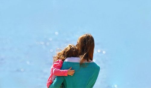 Rear view of woman carrying girl at beach