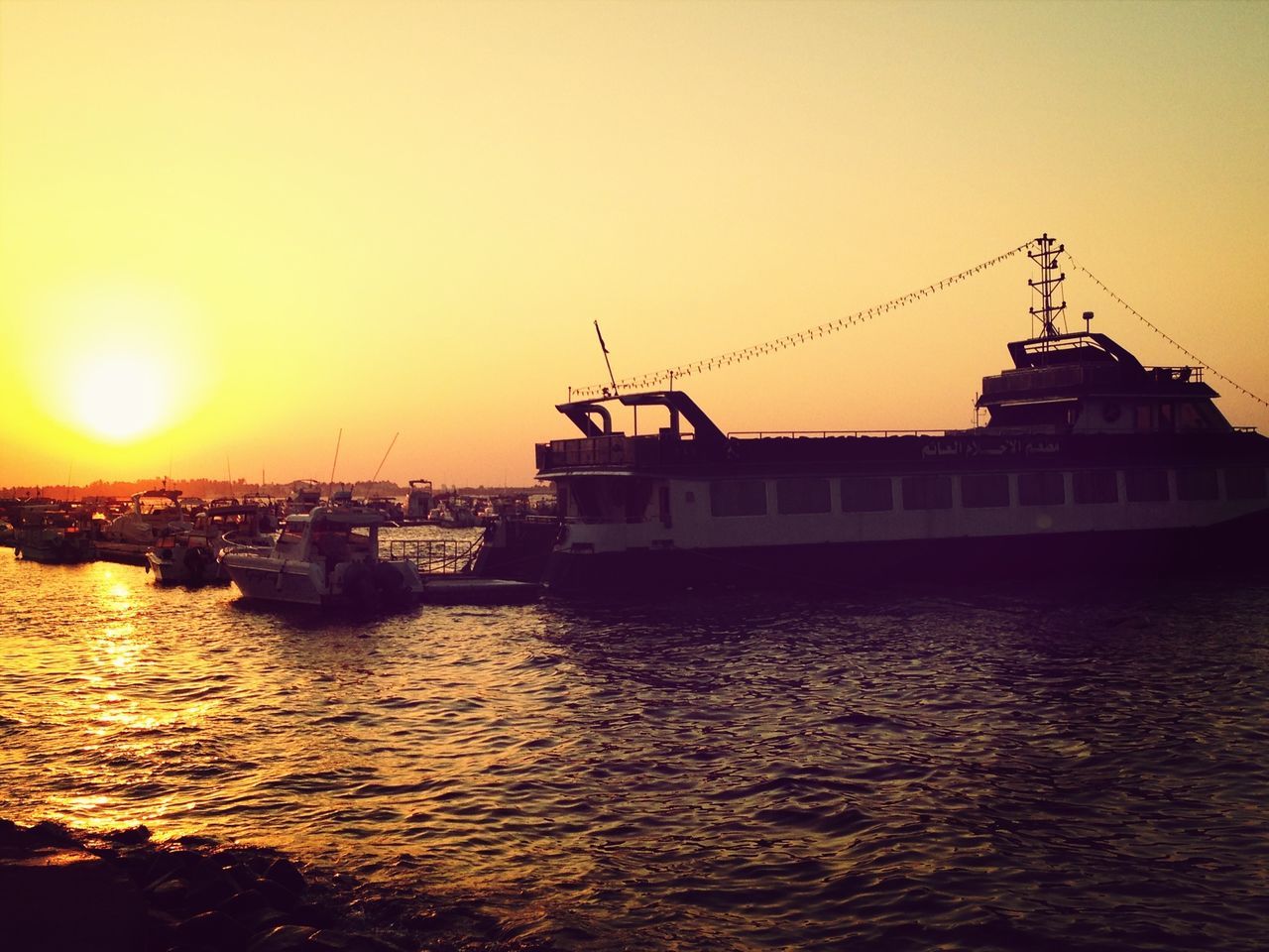 sunset, water, sun, nautical vessel, orange color, built structure, architecture, building exterior, sea, transportation, waterfront, mode of transport, crane - construction machinery, boat, clear sky, harbor, commercial dock, copy space, moored, sky