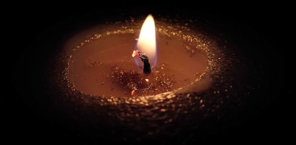 Close-up of lit candle against black background