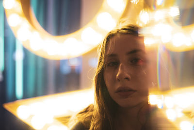 Close-up portrait of young woman with illuminated lights