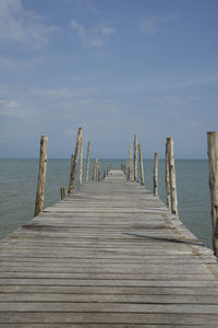 Wooden pier on sea against sky