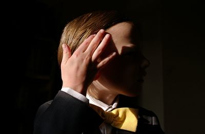 Close-up of man covering face against black background