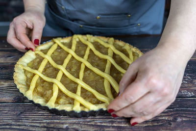 Women preparing delicious apple tart or pie large on wood table background.