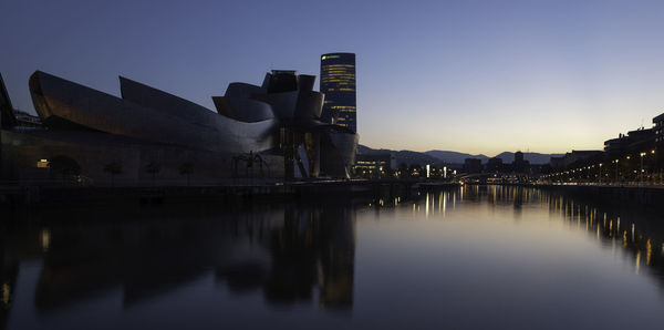 Reflection of illuminated buildings in river against sky