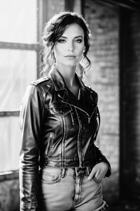 Portrait of young woman standing against wall