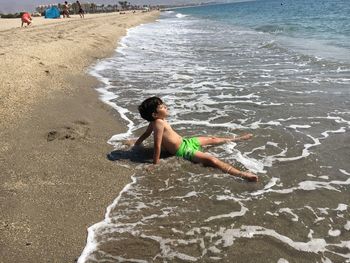 Full length of man relaxing on shore at beach